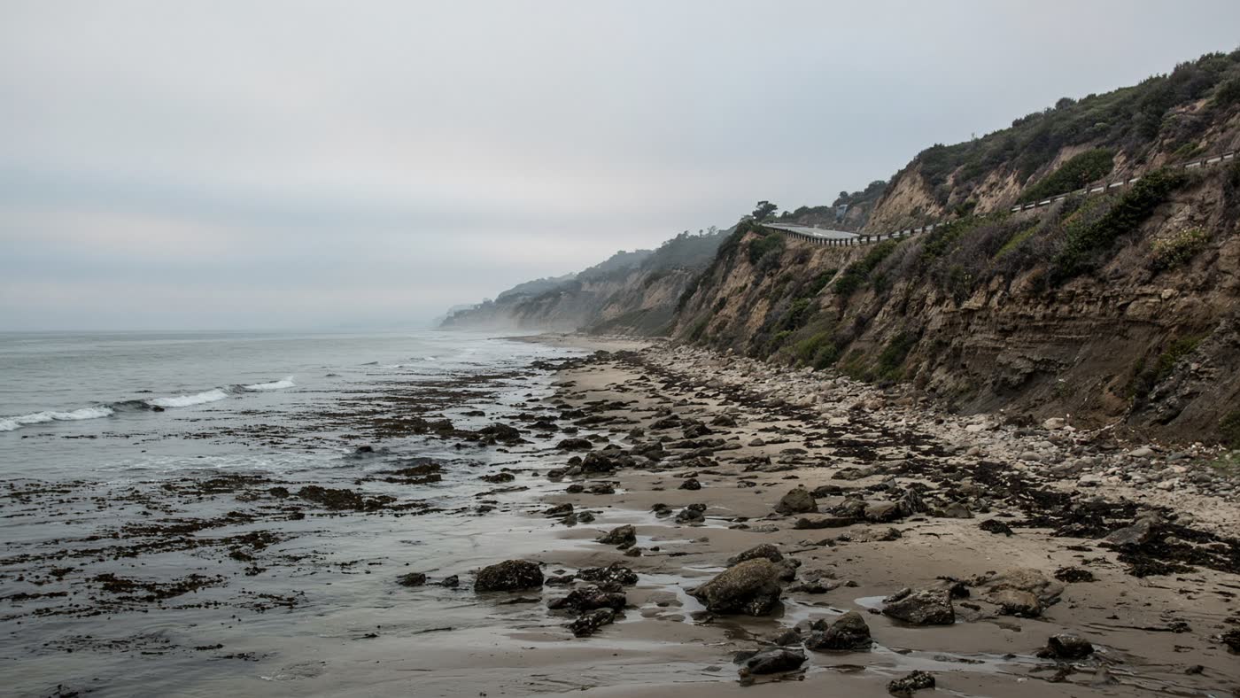 Narrow Malibu strand at Corral State Beach with kelp in the nearshore and bluffs above