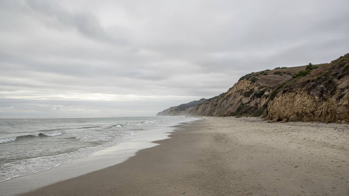 Long empty strand at County Line looking west under marine layer